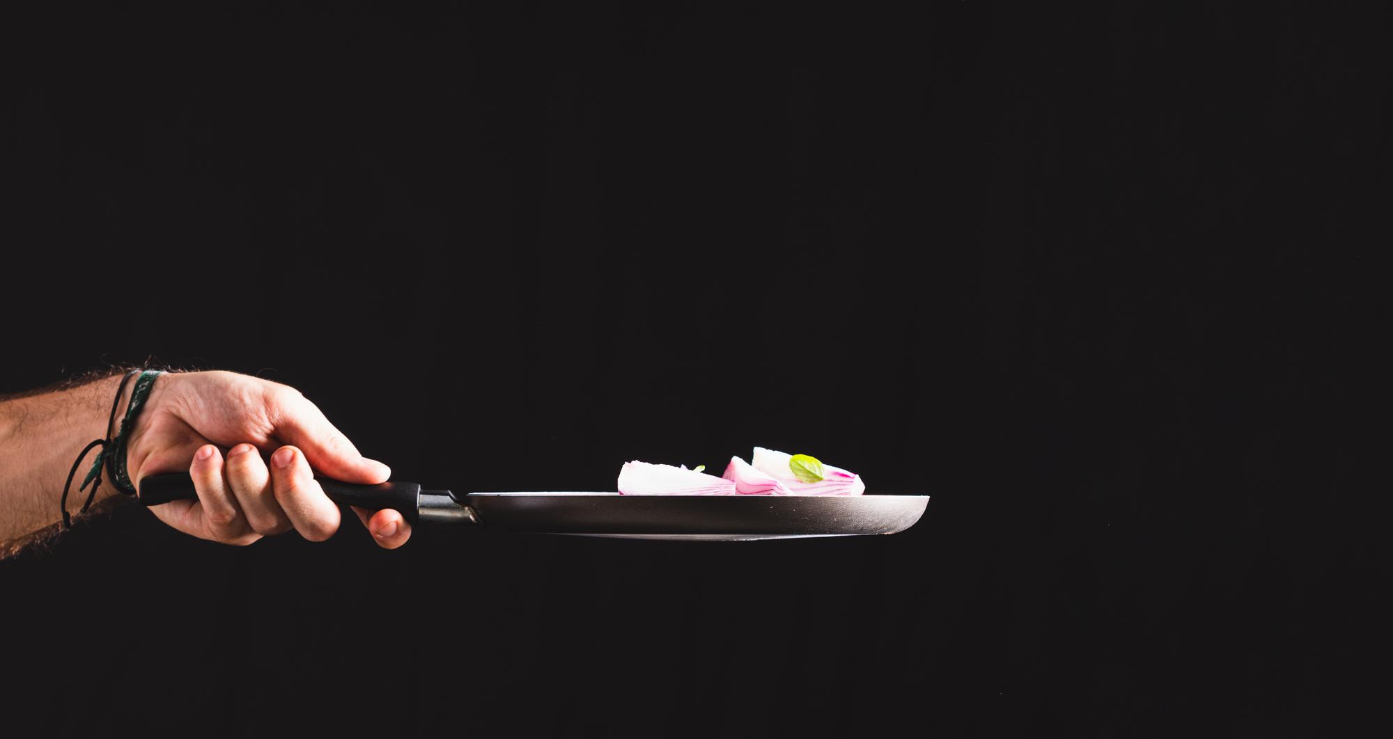 chef plating a modern dish on dark slate